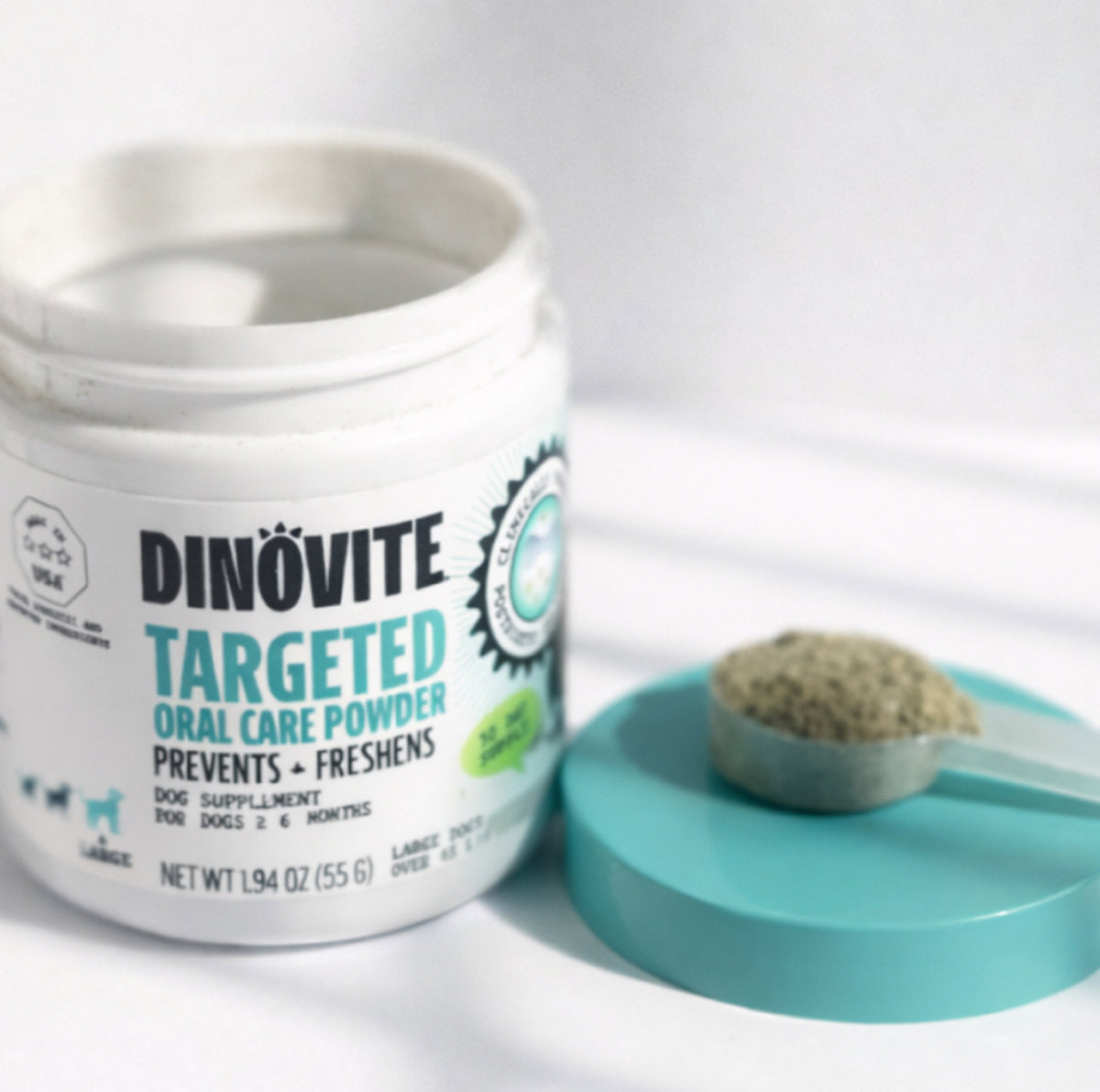 An open jar of Dinovite Targeted Oral Care Powder beside a scoop of powder